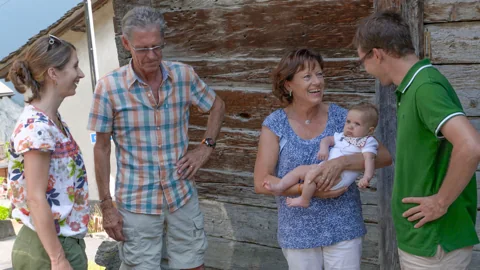 Quatre adultes réunis à l’extérieur ; une femme porte un bébé.