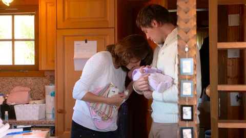 Deux femmes et un bébé dans l’entrée d’une maison.