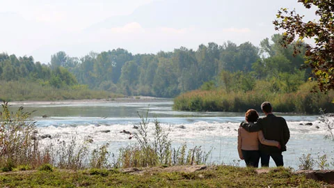 Deux personnes se tiennent enlacées au bord d’une rivière.